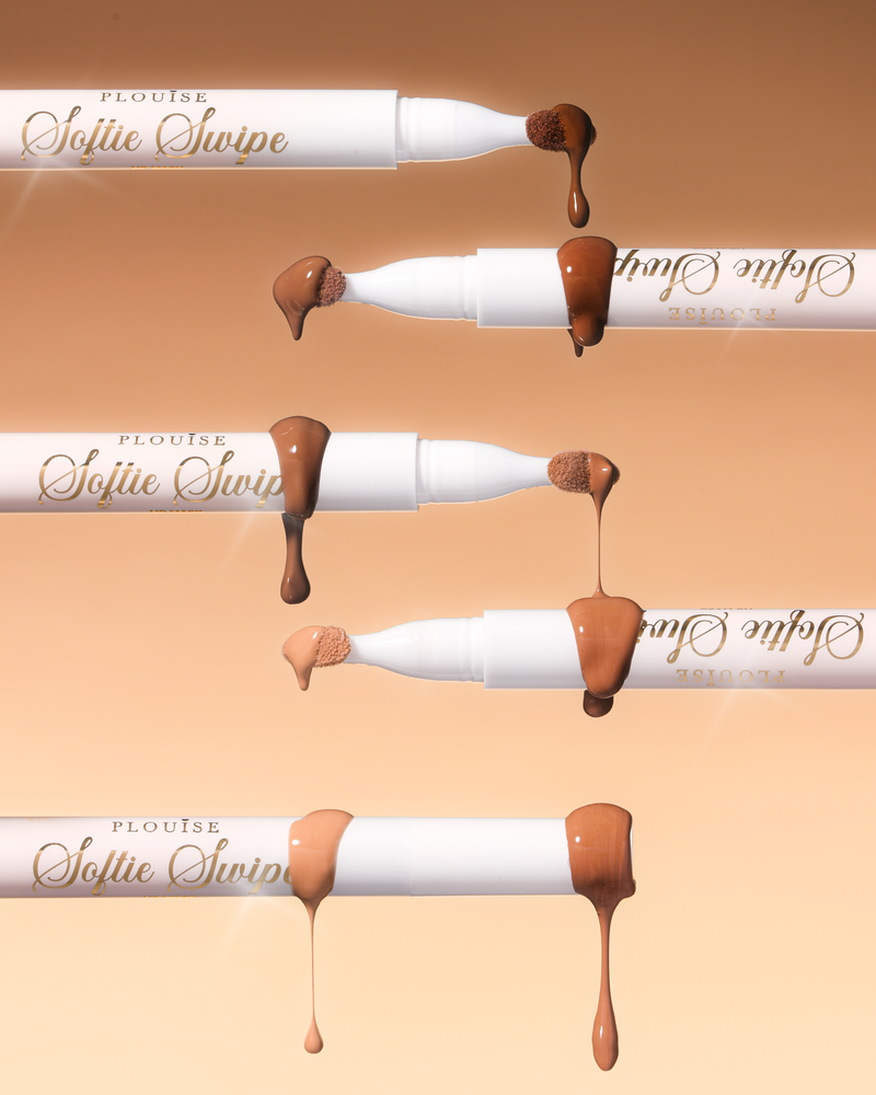 Een afbeelding van vijf P.Louise Softie Swipe Tinted Lip Masks waarbij het product van de uiteinden druipt en de verschillende tinten laat zien tegen een beige achtergrond