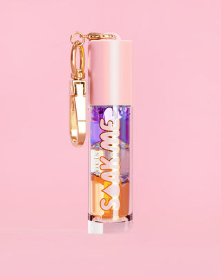 P. Louise Soak Me Lip Oil with colourful layered oil in a pink tube with a gold clasp on a pink background