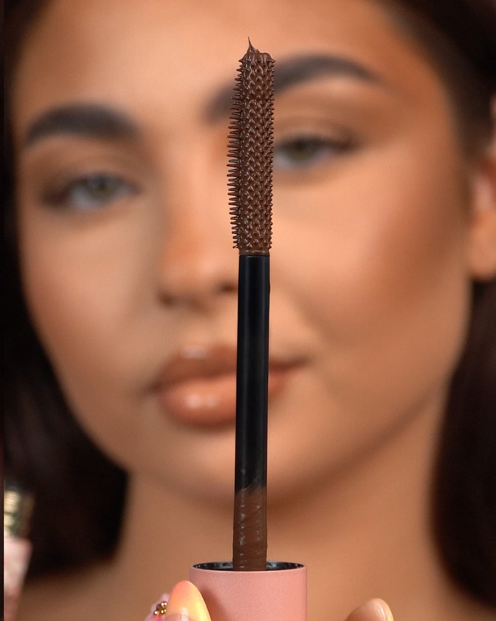 Close-up van een P.Louise Tearproof waterproof mascara-staafje dat voor een wazig gezicht wordt gehouden