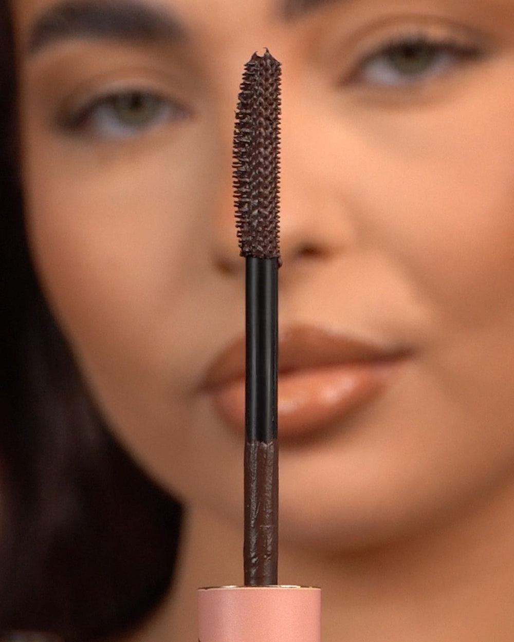 Close-up van een P.Louise Tearproof waterproof mascara-staafje dat voor een wazig gezicht wordt gehouden