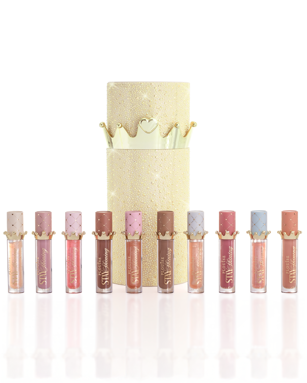 A set of ten P.Louise Christmas stay shining lip oil products arranged in a row in front of a glittery gold cylindrical lip oil box with a gold crown lid, on a clean white background.