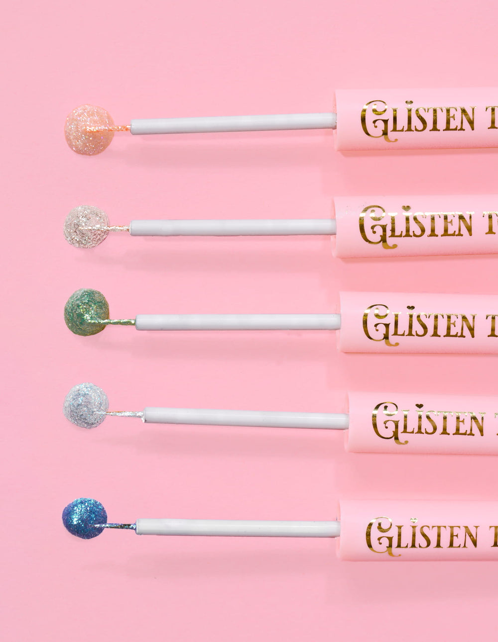 5 P.Louise Glisten To Your Heart glitter eyeliners met een druppel van het product aan het uiteinde tegen een roze achtergrond