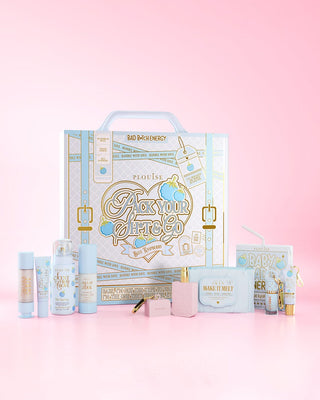 Light blue skincare products in front of the Pack Your Shit And Go Blue Raspberry suitcase against a pink background