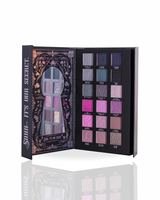 Page 2 of a halloween eyeshadow palette by P.Louise showing 16 shades, displayed open to show both the decorated black outer cover with a mirror and the inner palette containing various shades of purple, pink, blue, and gray.