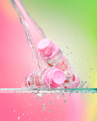 Pink Just A Swipe watermelon scented scented micellar water bottles with a colourful splash effect on a pink and green gradient background
