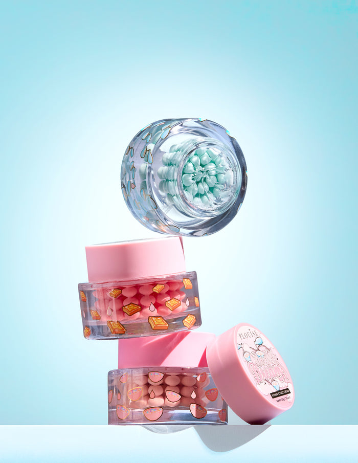 Drie kleine potjes met kleurrijke vitamine C-capsule in een gel op een lichtblauwe achtergrond