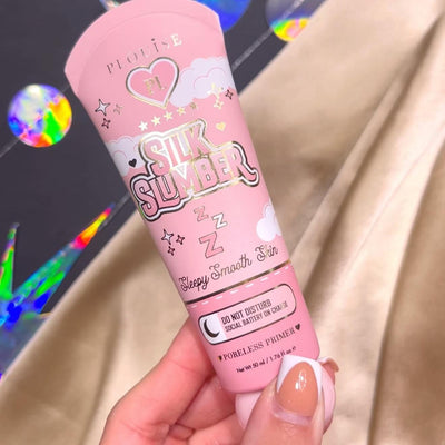 Een persoon die een tube P.Louise Silk Slumber Poreless Primer vasthoudt met een roze achtergrond en cosmetische productdetails.