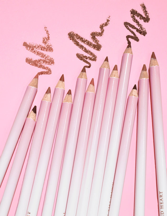 Een afbeelding van meerdere P.Louise Ultimate Definition Sharpenable Lip Liners gegroepeerd, met een product erboven getekend op een roze achtergrond