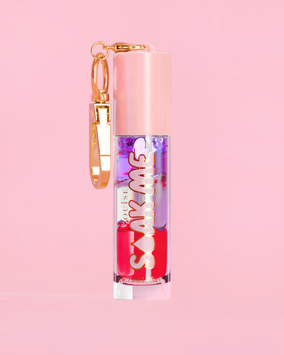 P. Louise Soak Me Lip Oil met kleurrijke gelaagde olie in een roze tube met gouden sluiting op een roze achtergrond